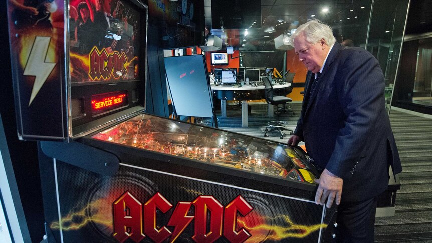 Clive Palmer plays on a pinball machine as he waits to do a breakfast radio interview.