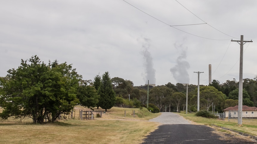 A country street with power stacks in the background