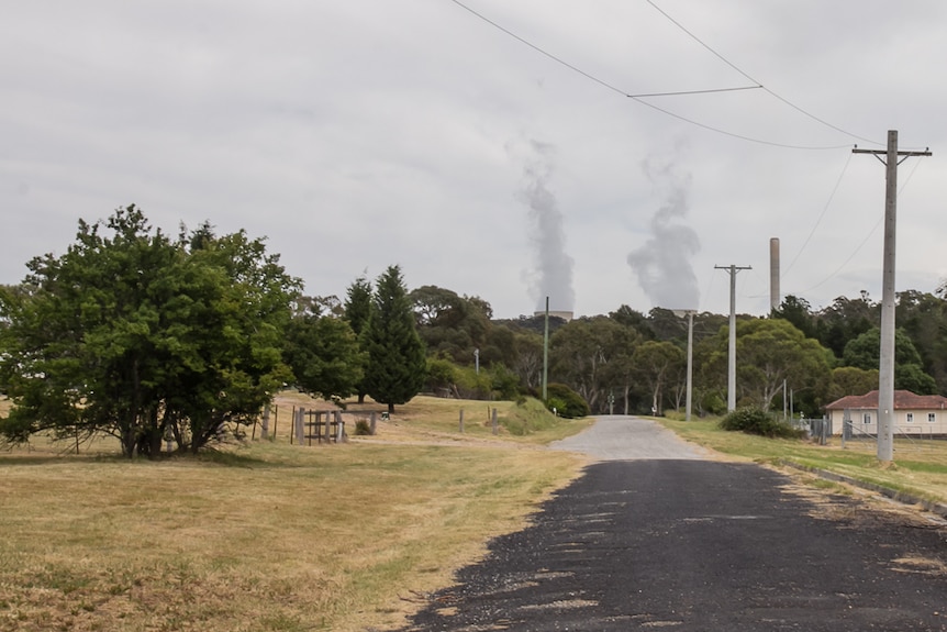 A country street with power stacks in the background