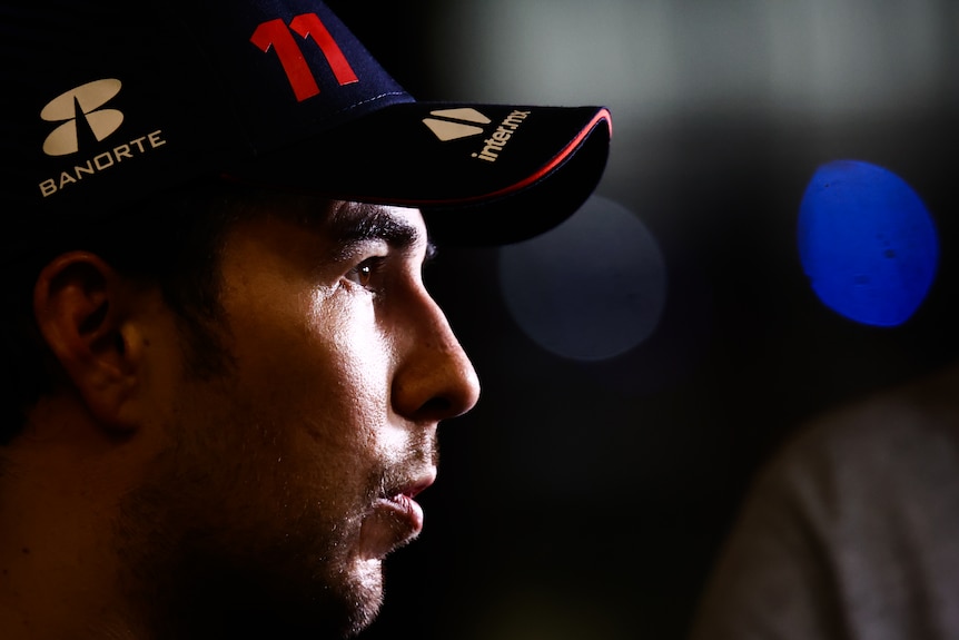 A man, wearing a blue cap with the number 11, at night, with a spotlight on his face.