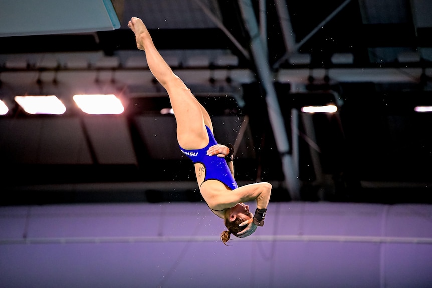 Melissa Wu upside down as she dives, holding her head and her stomach