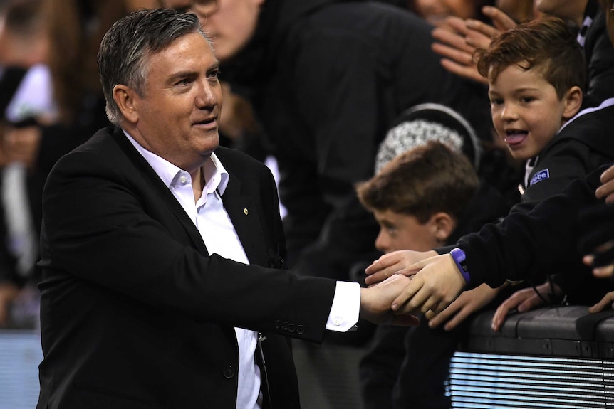 The Collingwood Football Club AFL president shakes hands with spectators at a match in Melbourne.