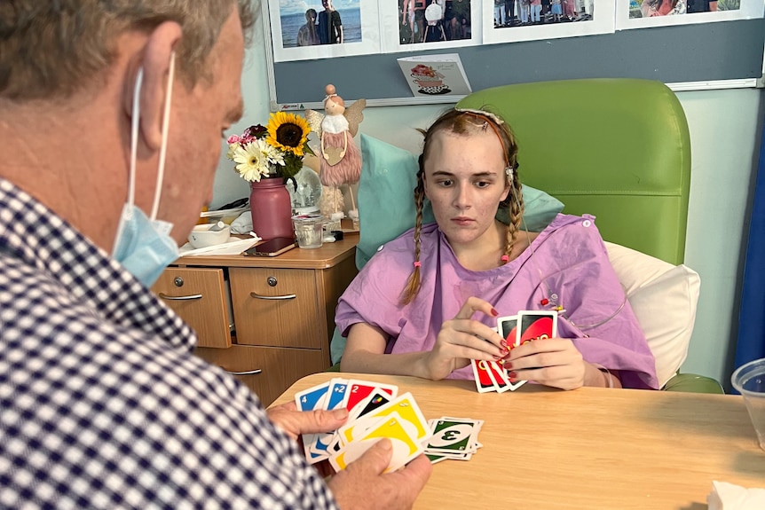 Dad playing cards with his adult daughter who's in hospital
