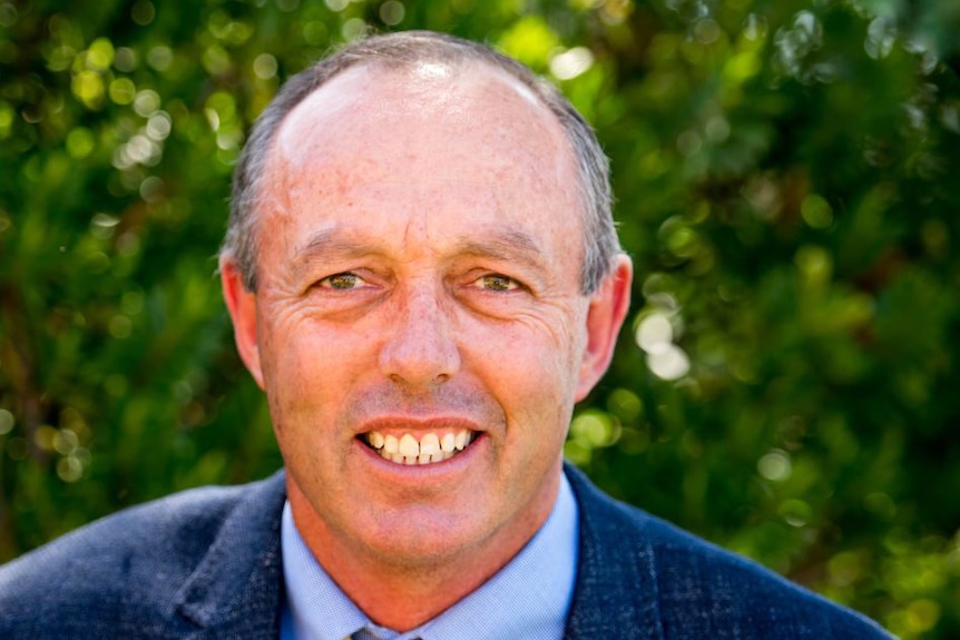 A head and shoulders shot of Ken Seymour wearing a suit and tie and smiling at the camera.