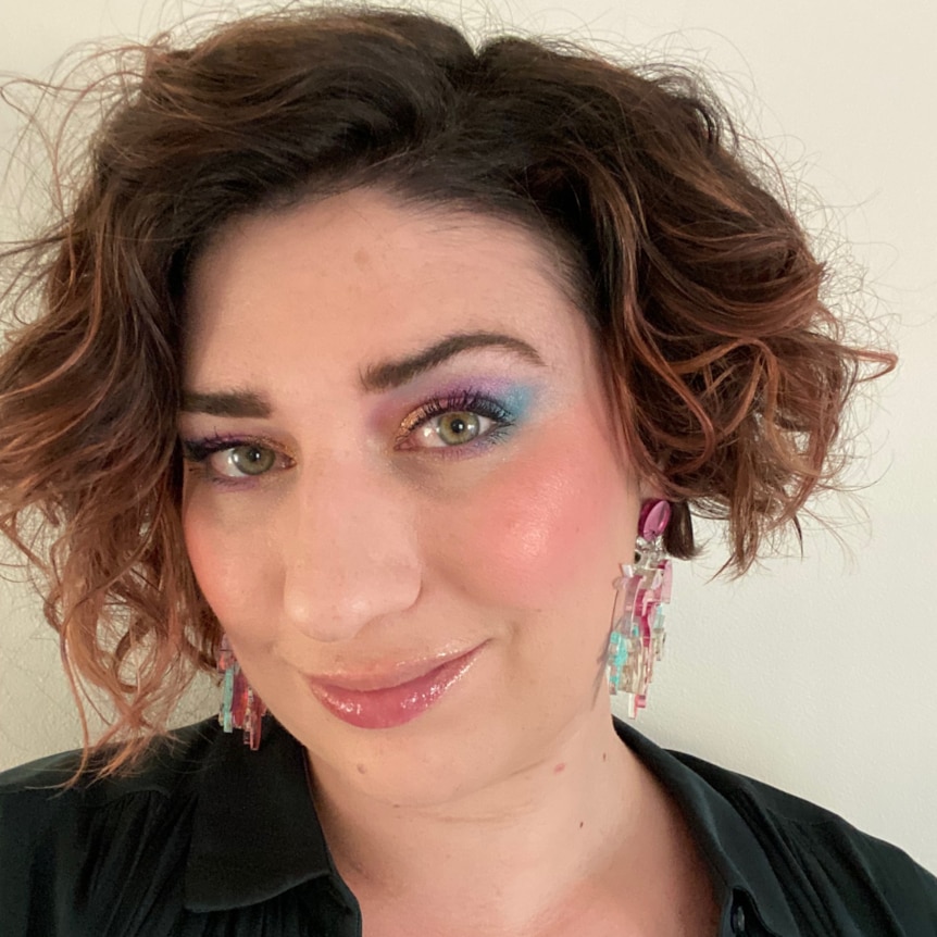 A selfie of Lauren Beckman with pink and blue eyeshadow and short curly hair