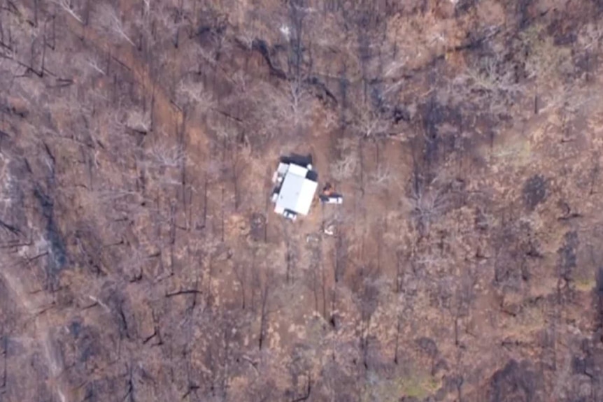 Aerial shot of house surrounded by burnt bushland