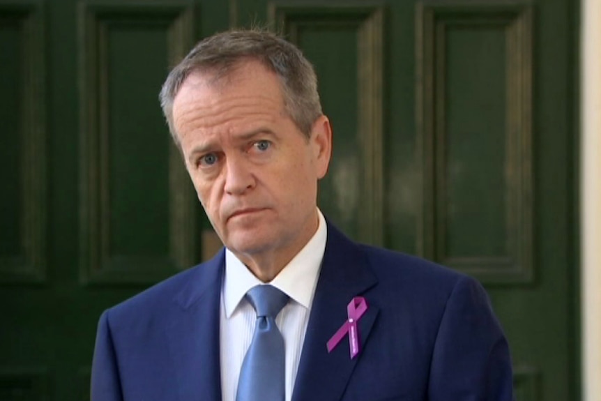Bill Shorten stands behind a microphone as he listens to a question from the media.