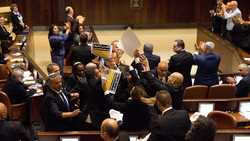 Israeli Arab members hold signs in protest as security pushes them out of Israel's parliament.
