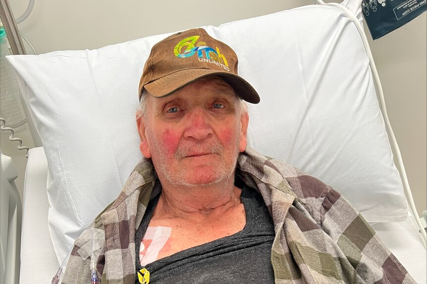 Man wearing hat lying on hospital bed.