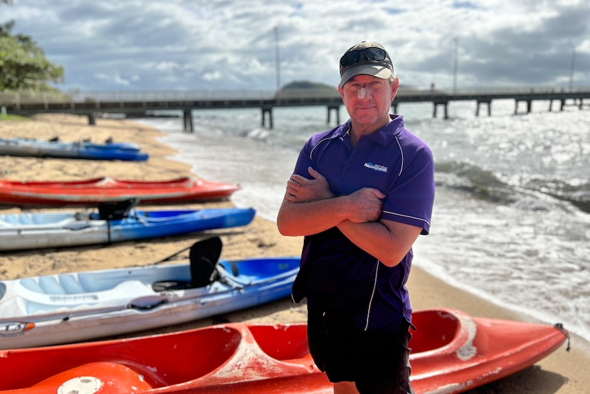 Brad Madgwick stands on the beach near kayaks
