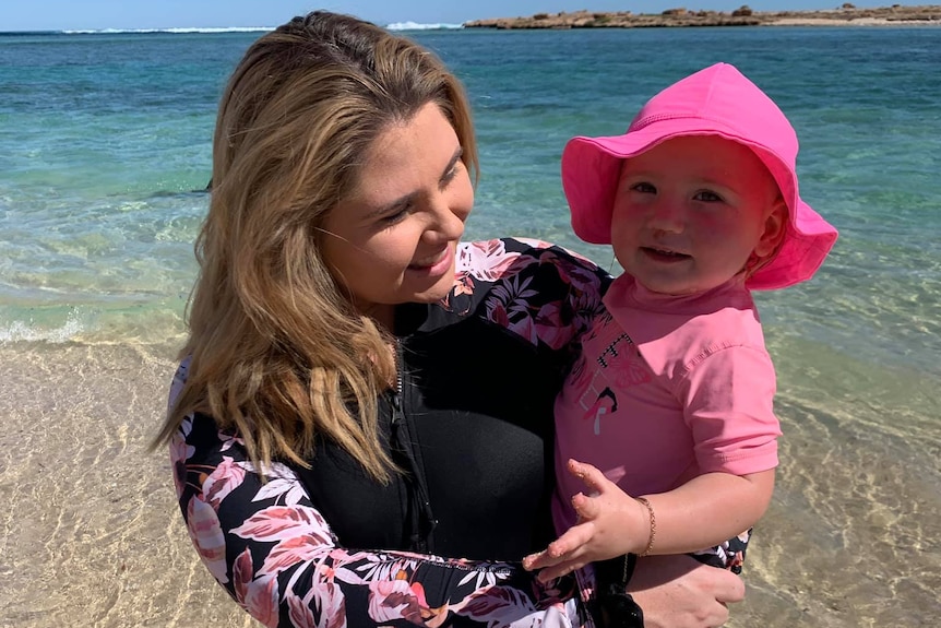 Ellie Smith standing on a beach holding Cleo Smith in her arms.