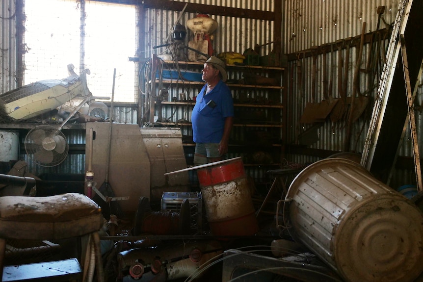 A man stands in a shed with mud covering everything. 