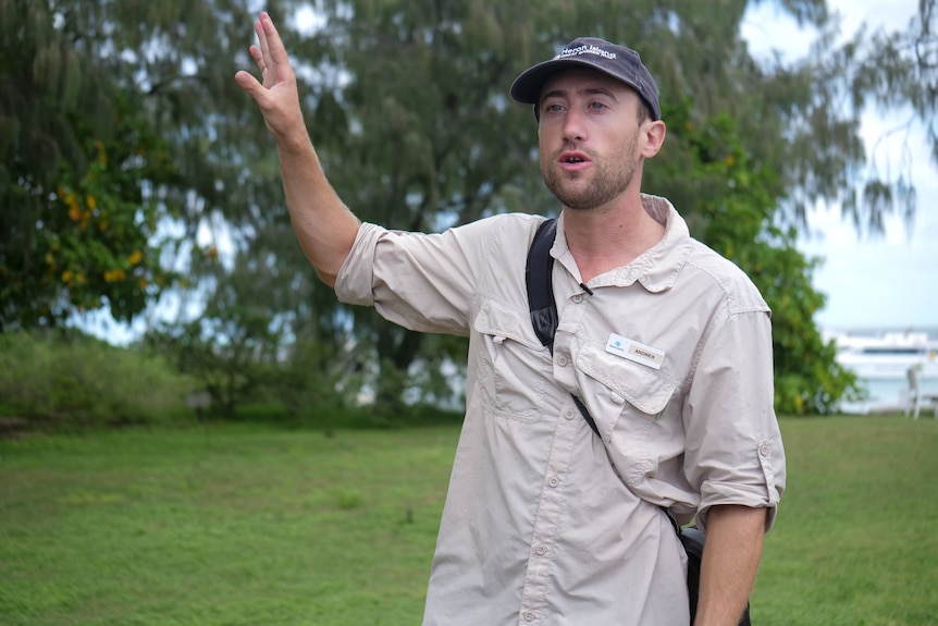 Andres speaking with his arm in the air, greenery behind.