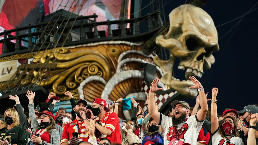 Super Bowl fans cheer in front of a pirate ship adorned with a skull at a stadium in Tampa.