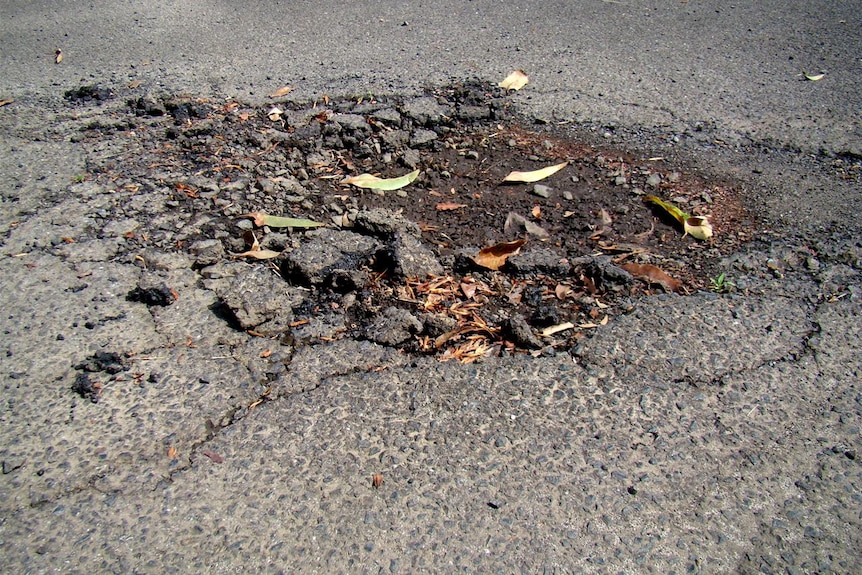 A close up of a pothole in a bitumen road