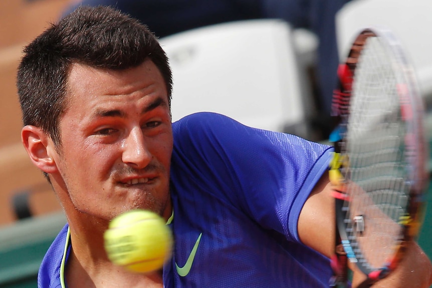 Bernard Tomic backhands at the French Open.