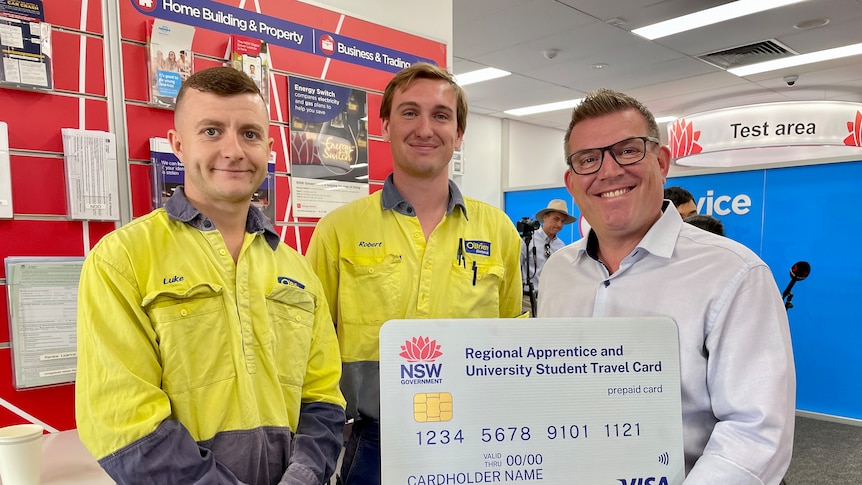 A man holds a giant card with two men in high-vis