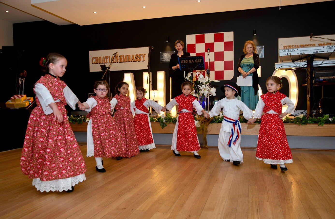 Children dressed in red and white hold hands during a performance