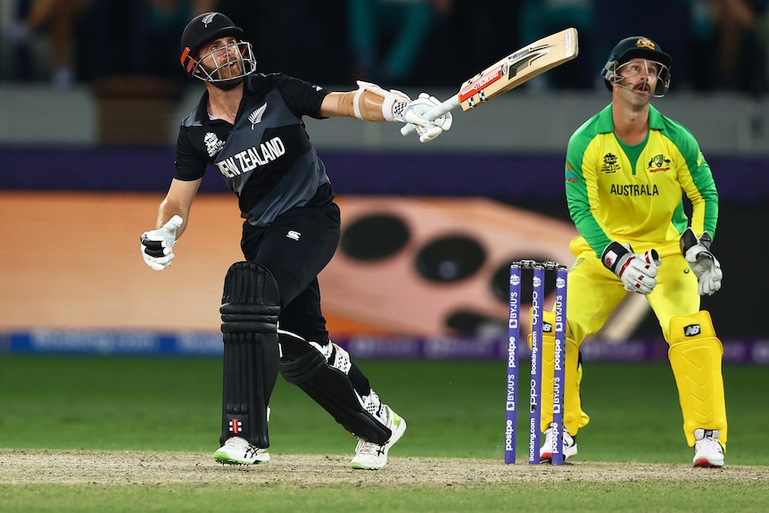 Kane Williamson hits a one-handed shot as Matthew Wade looks on.