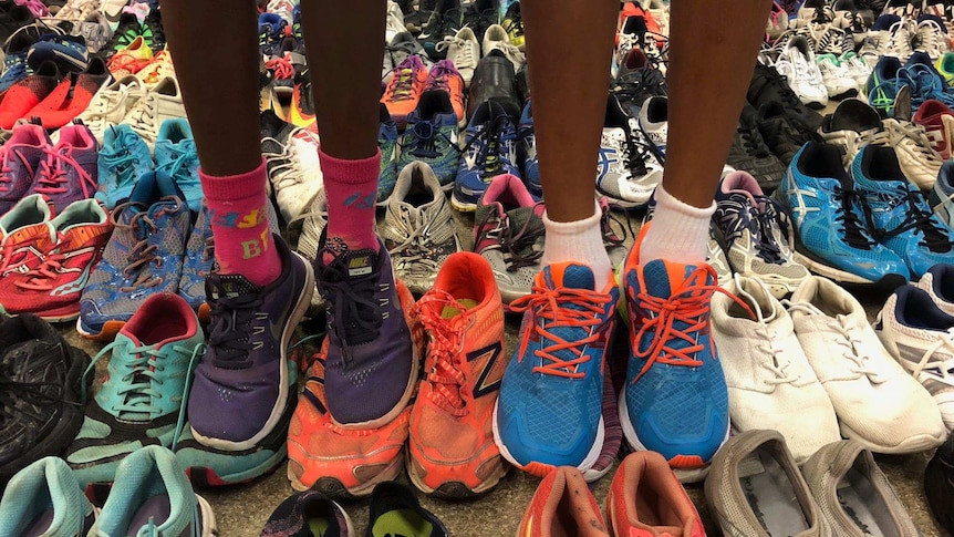 Legs of two children among a sea of colourful running shoes