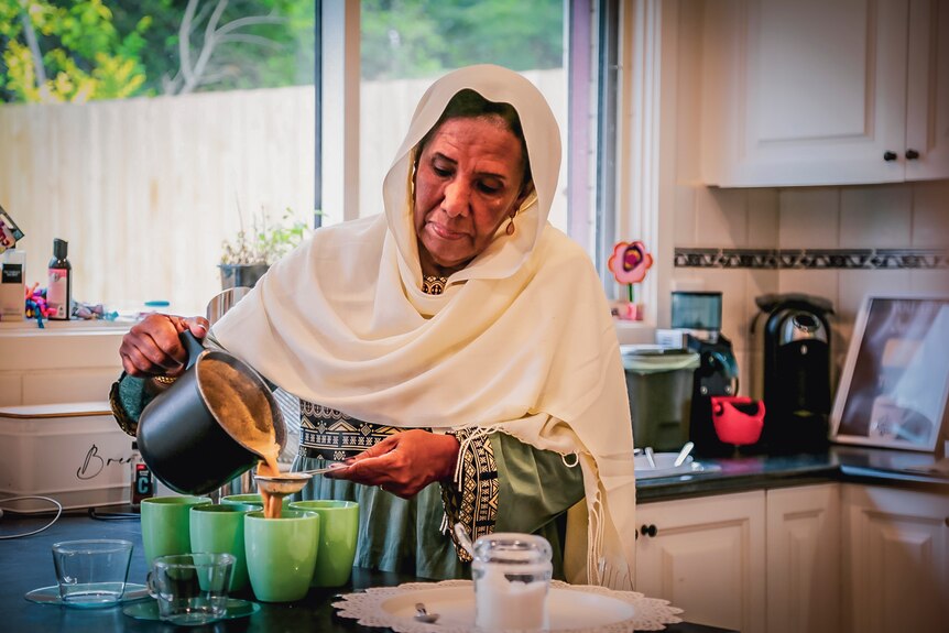A Muslim woman pouring tea in a kitchen