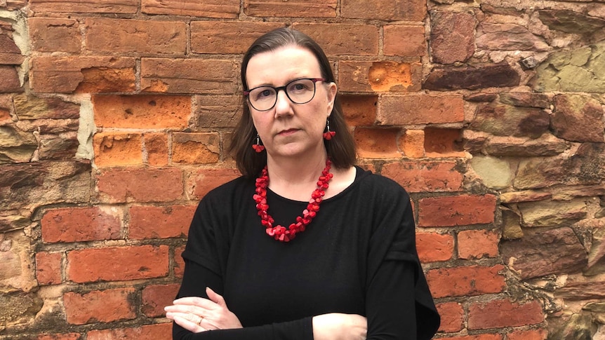 Karen Bentley stands against a wall with her arms crossed.