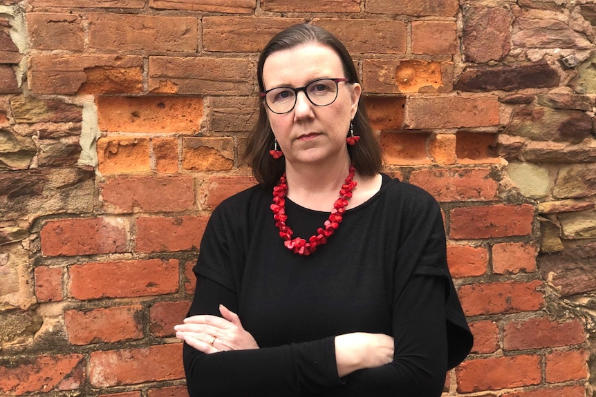 Karen Bentley stands against a wall with her arms crossed.