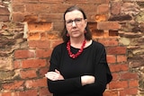 Karen Bentley stands against a wall with her arms crossed.
