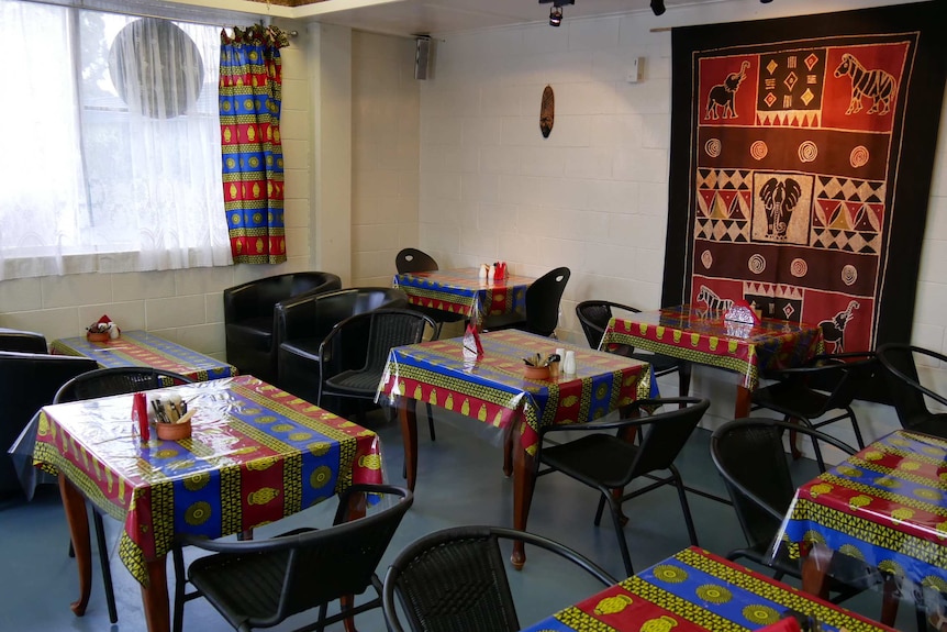 Tables and chairs set up with colourful African-style table clothes and wall hangings.