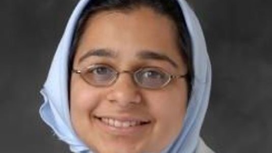 a woman with glasses and blue headwear looks at the camera