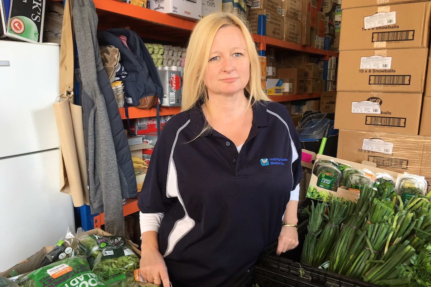 Melanie Kent standing with boxes of fresh greens.