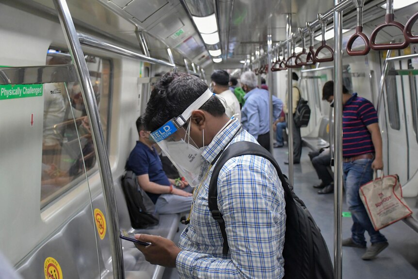 The interior of an Indian metro train with commuters wearing PPE.
