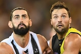Brodie Grundy and Toby Nankervis push against each other as they stare at the ball in the air.