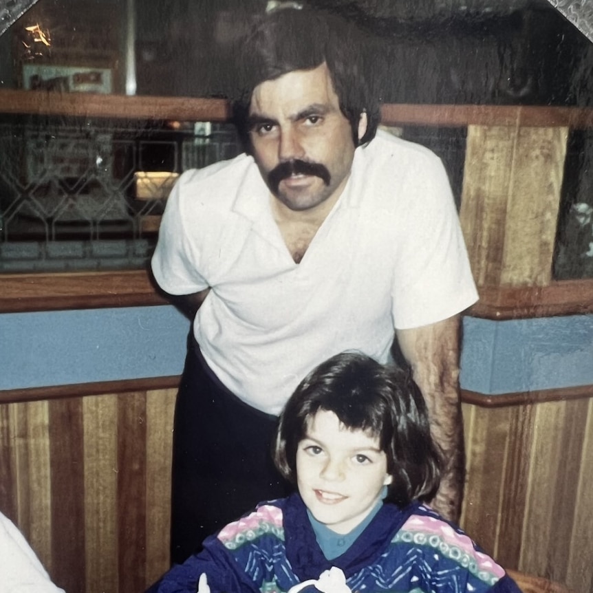 a dark haired man with moustache leans over his daughter at Hungry Jacks birthday party