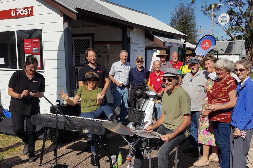 Group of people and radio and music equipment set up outside Quaama General Store.