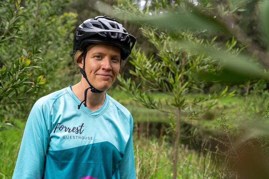 a woman wearing a bike helmet smiles at the camera.