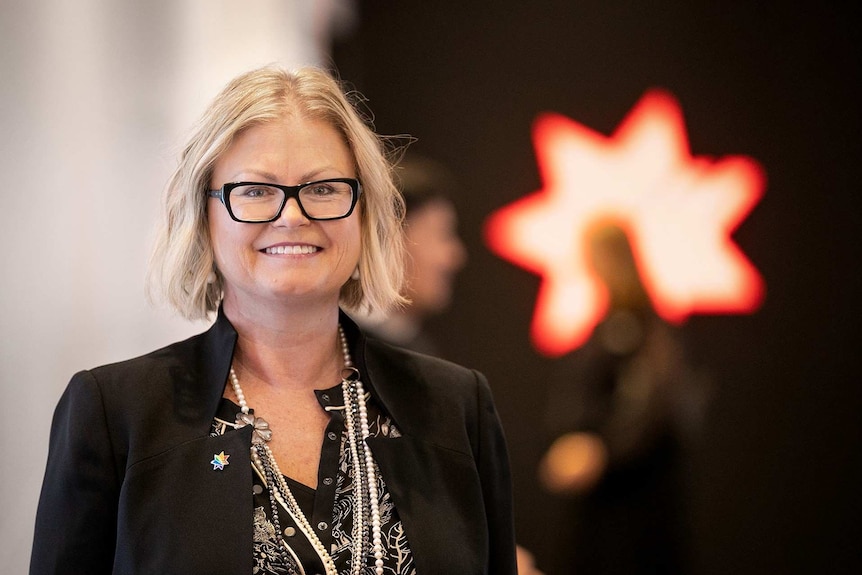 Rachel Slade stands in front of an NAB logo.