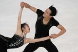 Male figure skater smiles as he spins his female partner.