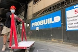 A worker pushes a trolley on a Probuild site in A'Beckett St, Melbourne with branding in background.