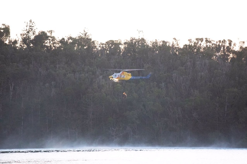 Helicopter hovering above water winching woman at Cid Harbour.