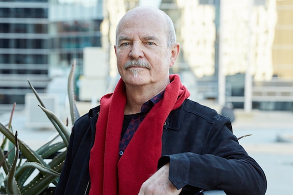 Colour photograph of poet and novelist Philip Salmon posing for a photography on a city rooftop.