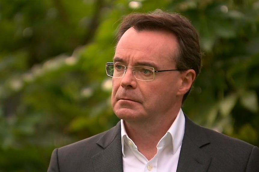 A man with dark hair and glasses.