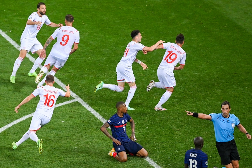 Switzerland players run off as French players kneel on the ground