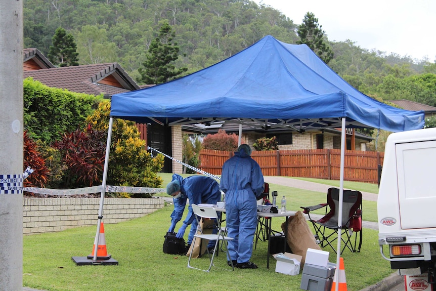 Forensic officers underneath a canopy in front of the home with police tape.