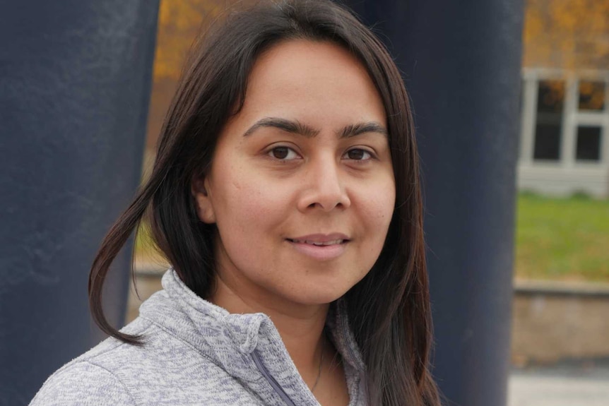 Dark-haired woman wearing grey hoodie