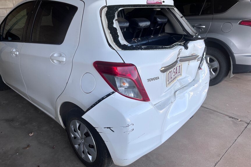 A small white Toyota is damaged from behind