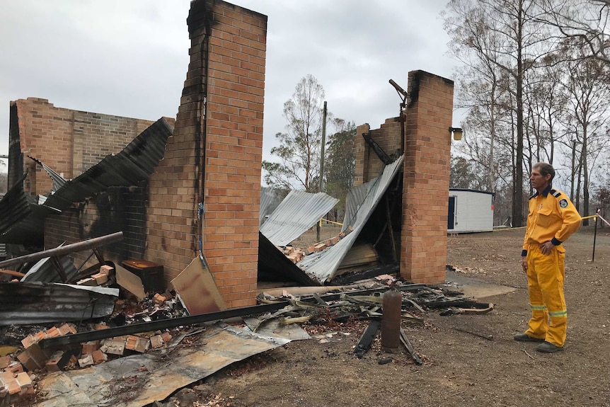 A firefighter looking at the wreckage of a burnt out house