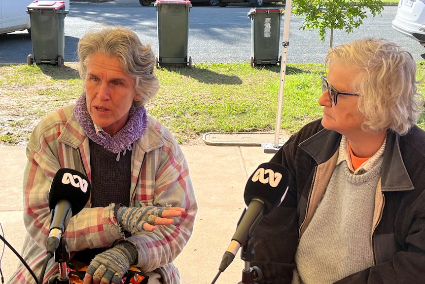 two ladies sit at a chair speaking into microphones