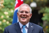 Scott Morrison laughs in front of an Australian flag