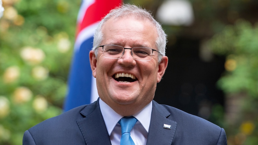 Scott Morrison laughs in front of an Australian flag